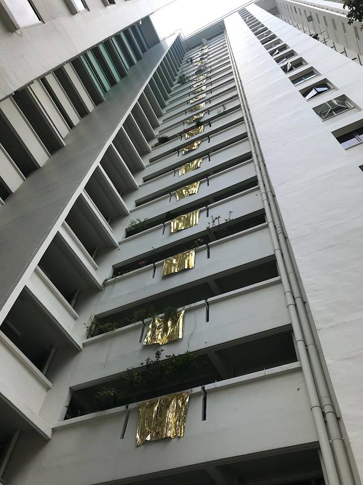 Woman puts up gold foil flags over apartment building to showcase her art - Alvinology